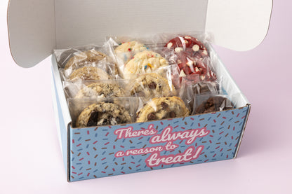 Open treat box filled with individually wrapped cookies in various flavors, including chocolate chip, cookies & cream, red velvet, and confetti cake. The box exterior reads, "There's always a reason to treat!" against a blue background with sprinkles.