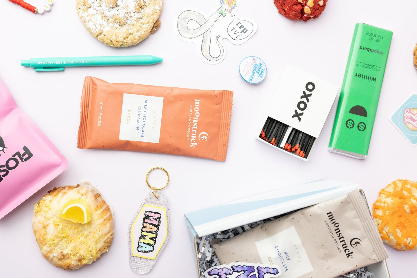 Assorted snacks and products including a green box, orange packet, and cookies on a white surface.