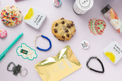 Assorted items including a cookie, mints, and keychains on a light background